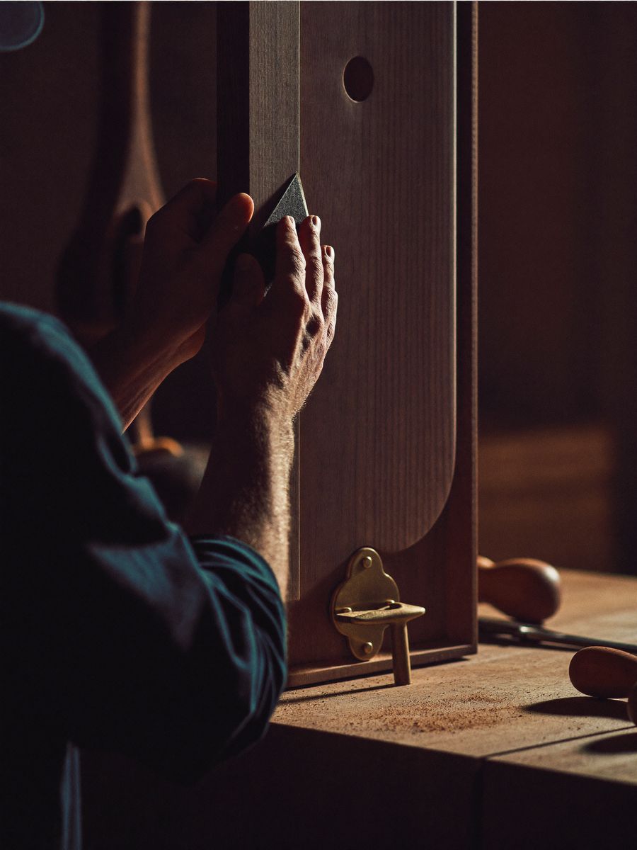 Craftsman hand-finishing a curved walnut panel in the joinery workshop