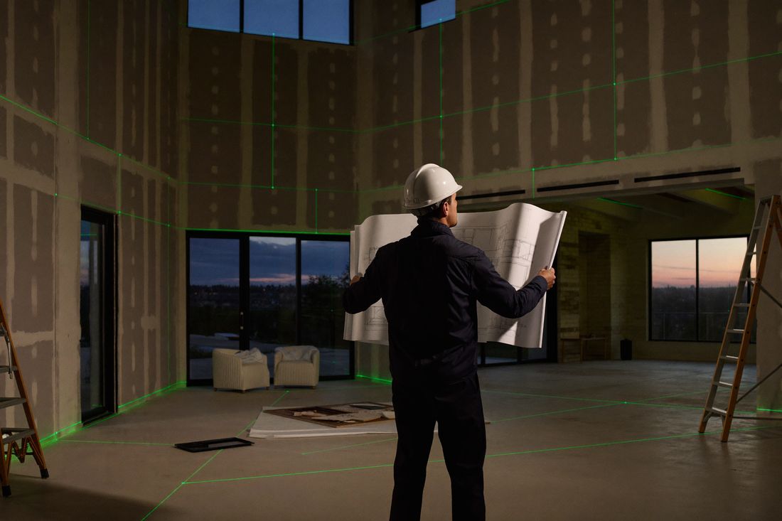 Site supervision — reviewing drawings inside an unfinished interior